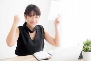 Beautiful young asian woman working laptop computer at office, businesswoman looking graph diagram analysis statistic data with excited and success, girl using notebook, business concept. photo