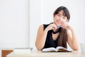 Beautiful portrait young asian woman smiling sitting study and learning writing notebook and diary in the living room at home, girl homework, businesswoman working on table, education concept. photo