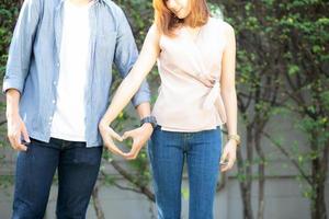 Closeup of happy couple fun making gesture heart shape with hand outdoor together, man and woman with relation feeling love with symbol and sign, lover and romantic concept. photo