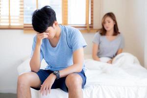 Asian young couple having problem of man worried impotent and unhappy at bedroom, trouble divorce of family with frustrated, husband having depression, conflict of love concept. photo