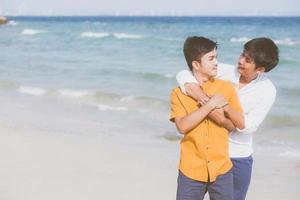 Homosexual portrait young asian couple standing hug together on beach in summer, asia gay going tourism for leisure and relax with romantic and happiness in vacation at sea, LGBT concept. photo