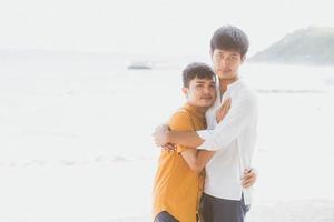 retrato homosexual joven pareja asiática de pie abrazo juntos en la playa en verano, turismo gay de asia para el ocio y relajarse con romanticismo y felicidad en vacaciones en el mar, concepto lgbt. foto