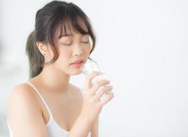 Beautiful portrait young asian woman caucasian smiling with nutrition thirsty and drinking glass of water mineral with fresh and happy, asia girl diet for healthy care and wellness, lifestyle concept. photo