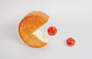 Roll of cheese like a pak-man swallows tomatoes from the table