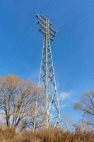 Lonely standing electric tower in a field in autumn against a clear sky backgroun photo