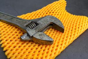 Old adjustable wrench for tightening nuts close-up on a yellow mat photo