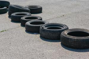 Old car tires lie on the asphalt in the form of a blockage on the race track photo
