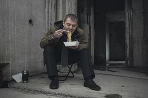 hombre de negocios en bancarrota obligado a comer comida barata en un edificio abandonado foto