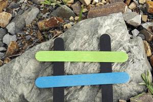 Colorful wooden stick on stone beach background. Copy space. Directly above. photo