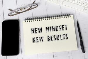 New mindset, new results text on notepad on white wooden desk. photo