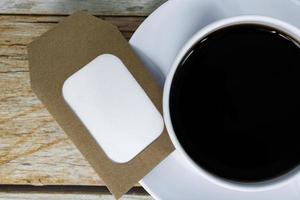 Notepad with cup of coffee on wooden background. photo