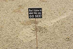 Motivational quote on chalkboard on sandy beach background photo