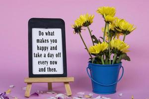 Motivational quote on note paper with frame - Do what makes you happy and take a day off every now and then. photo