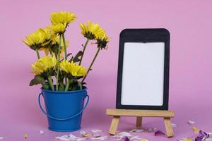 Note paper with frame and and flowers in blue bucket on pink background. photo