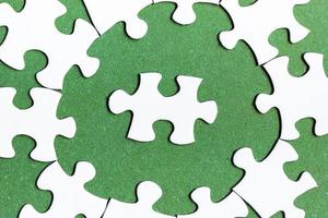 White jigsaw puzzle with some missing pieces on green background. Flat lay. photo