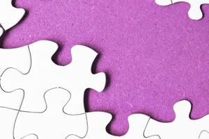 White jigsaw puzzle with some missing pieces on purple background. Copy space. photo