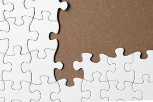 White jigsaw puzzle with some missing pieces on wooden background. Copy space. photo