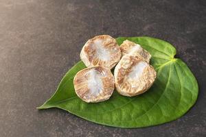 Betel nut or areca nut with betel leaf isolated on dark background. photo