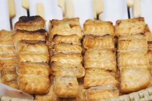 Close up of barbecue grill salmon skewers on wooden sticks, thai street food market photo