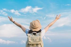 woman traveler with backpack holding hat and looking at the blue sky,  travel concept, space for text and atmospheric moment photo