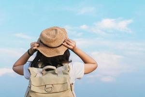 woman traveler with backpack holding hat and looking at the blue sky,  travel concept, space for text and atmospheric moment photo
