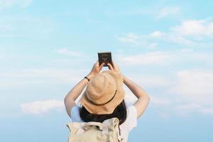 mujer viajera con mochila con sombrero y pasaporte de tailandia mirando el cielo azul, concepto de viaje, espacio para texto y momento atmosférico foto