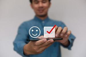 Businessmen wearing a light blue shirt to selecting the level of satisfaction score icons with copy space. Customer service experience and business satisfaction survey concept photo