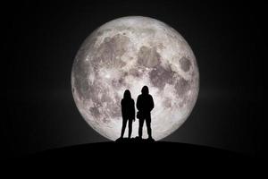silueta de hombre y mujer mirando la luna con esperanza de cumplimiento en el amor. elementos de esta imagen proporcionada por la nasa. foto