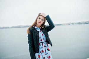 Stylish girl in leather jacket at winter day against frozen lake. photo