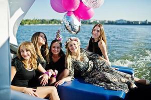 Five girls wear on black having fun at yacht against lake at hen party. photo