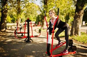 la joven tiene el entrenamiento y hace ejercicio al aire libre en simuladores callejeros. deporte, fitness, concepto de entrenamiento callejero. foto