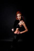 Fashion model red haired girl with originally make up like leopard predator isolated on black. Studio portrait. photo