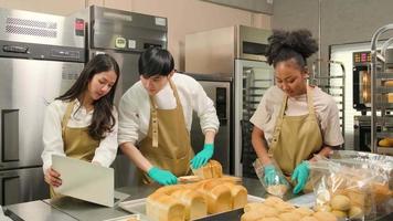 três jovens amigos e parceiros de inicialização de massa de pão e alimentos de confeitaria ocupados com trabalhos de panificação caseiros enquanto preparam pedidos on-line, embalam e entregam na padaria, pequeno empresário video