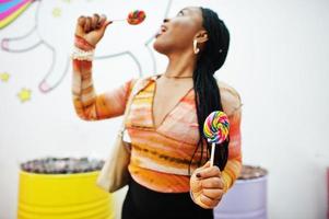 dama milenaria afroamericana en la tienda de dulces con piruletas. foto