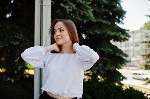 Portrait of an amazing woman in white blouse and wide black pants posing with pine trees on the background. photo