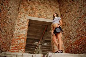 Girl wear on shorts with big headphones at abadoned factoty with brick walls. photo