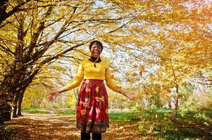 African american girl at yellow and red dress at golden autumn fall park. photo