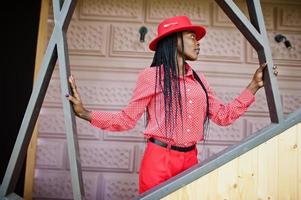 Pretty braids business african american lady bright bossy person friendly wear office red shirt, hat and trousers. photo