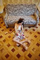 Portrait of an amazing woman in beautiful dress laying on the wooden floor. photo