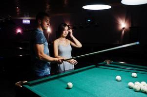 mujer vestida jugando al billar con un hombre en un pub. foto