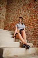 Girl wear on shorts with big headphones at abadoned factoty with brick walls. photo