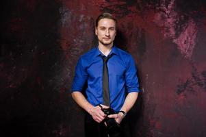 Studio portrait of stylish professional photographer man with camera, wear on blue shirt and necktie. photo