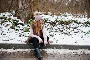 chica elegante con abrigo de piel y sombreros en el día de invierno en el borde de la carretera. foto