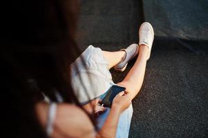 Close-up photo of a woman's hand holding a phone with earphones plugged into it.