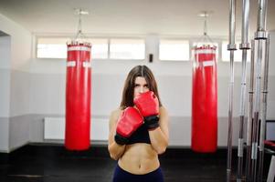 Young beautiful woman, wear on boxing gloves doing exercises and working hard in gym and enjoying her training process. photo