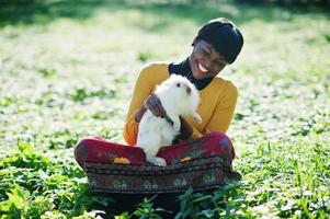 African american girl at yellow and red dress with white rabbit at hands. photo