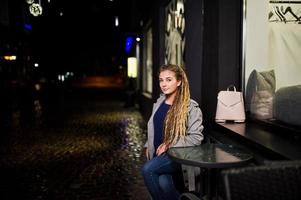 chica con rastas caminando por la calle de noche de la ciudad. foto