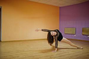 Curly brunette plus size model doing acrobatic at dance room. photo