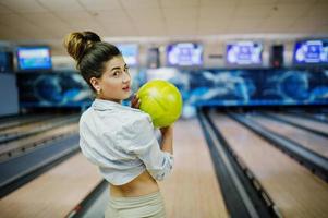 Girl with bowling ball on alley played at bowling club. photo