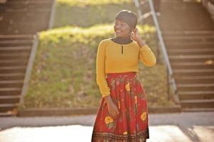 African american girl at yellow and red dress at golden autumn fall park. photo